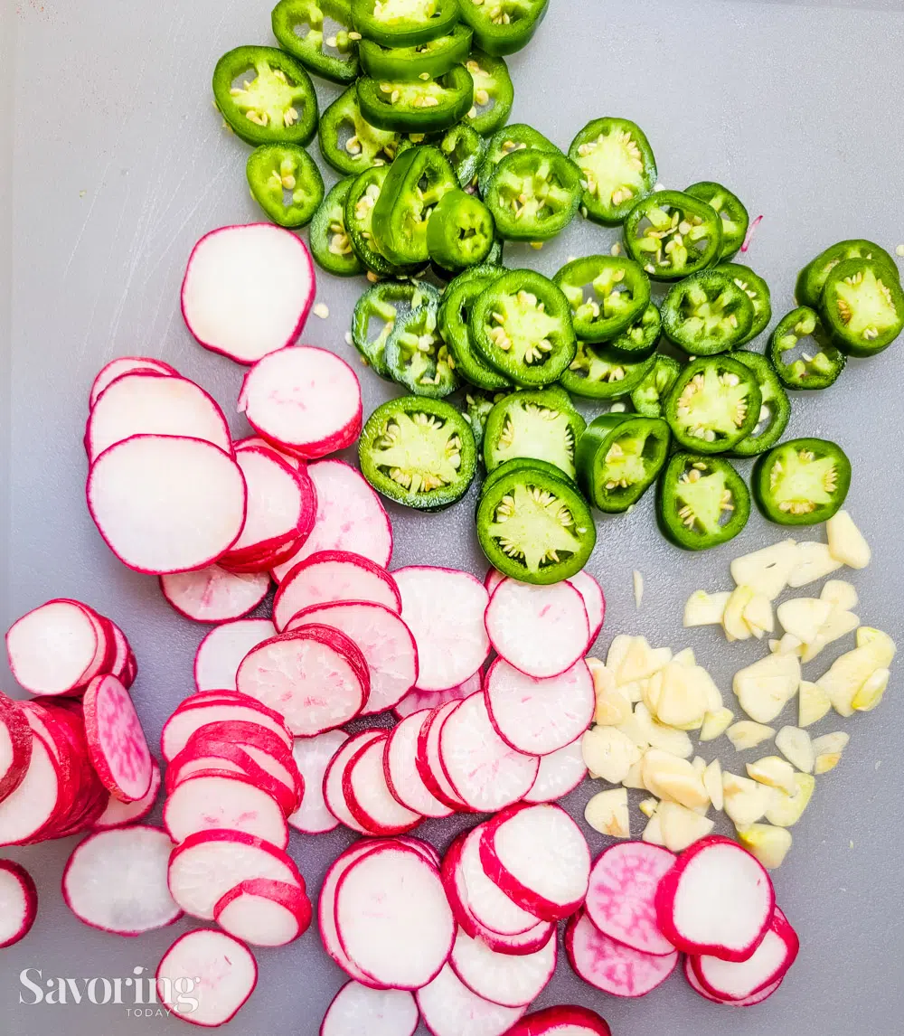 Radishes, jalapenos, and garlic sliced on a cutting board