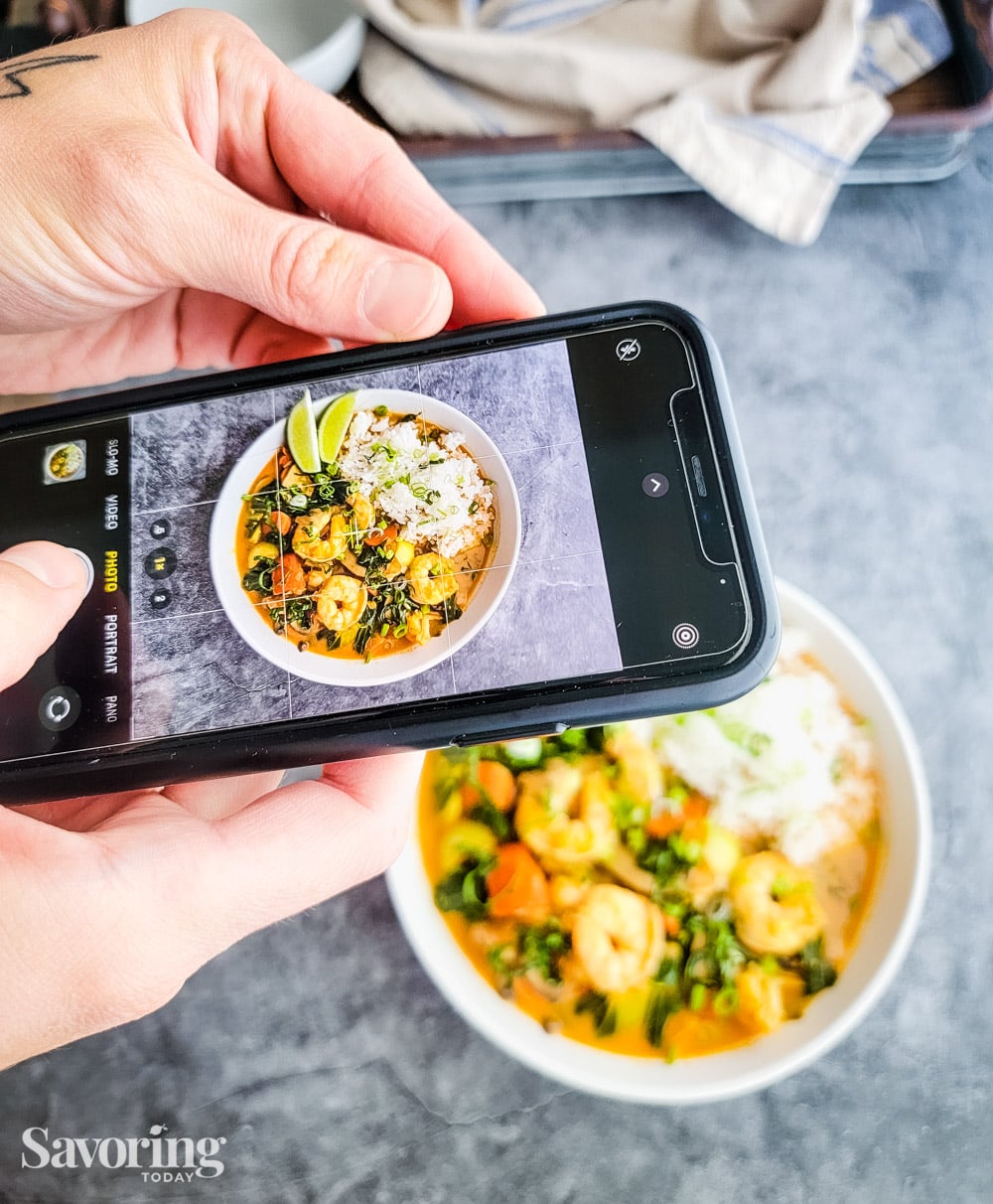 an iphone held over a bowl of food taking a photo
