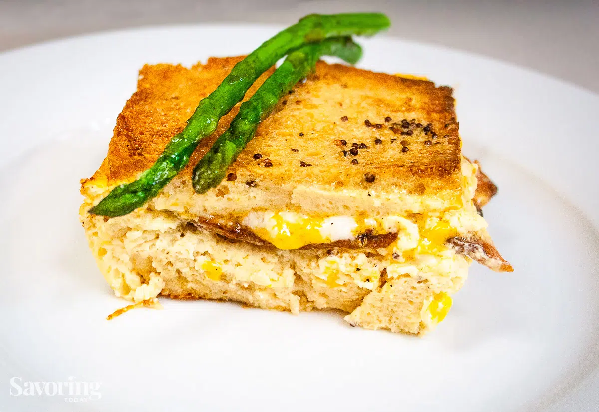 Sandwich casserole served on a white plate with steamed asparagus
