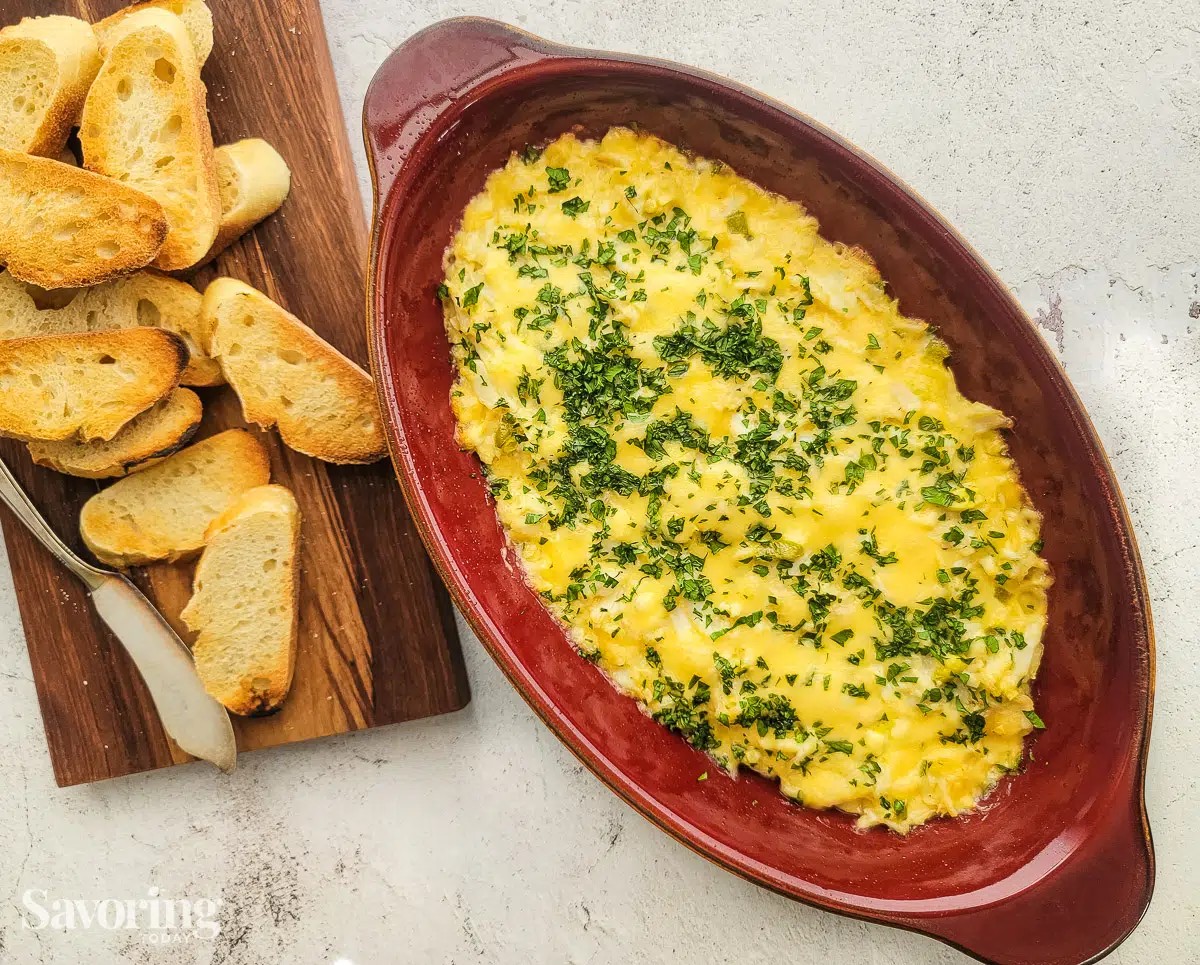 Fresh crab dip hot from the oven in a red baking dish with bread toast