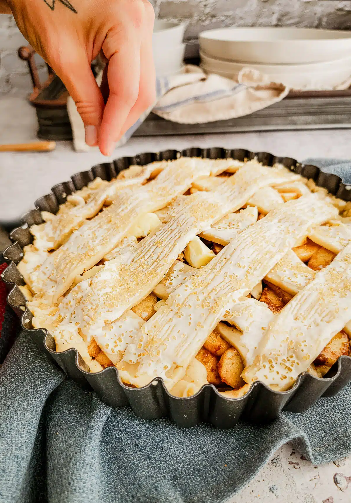 sprinkling sugar over a pie crust ready for the oven