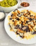 chicken nachos with black beans and cheese on a white plate