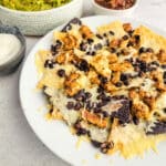 chicken nachos with black beans and cheese on a white plate