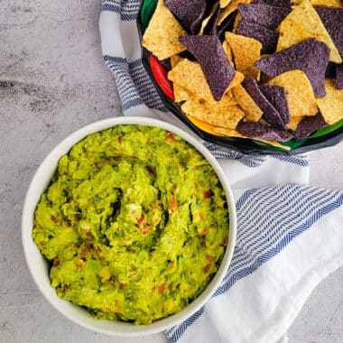 guacamole in a bowl with chips on a counter