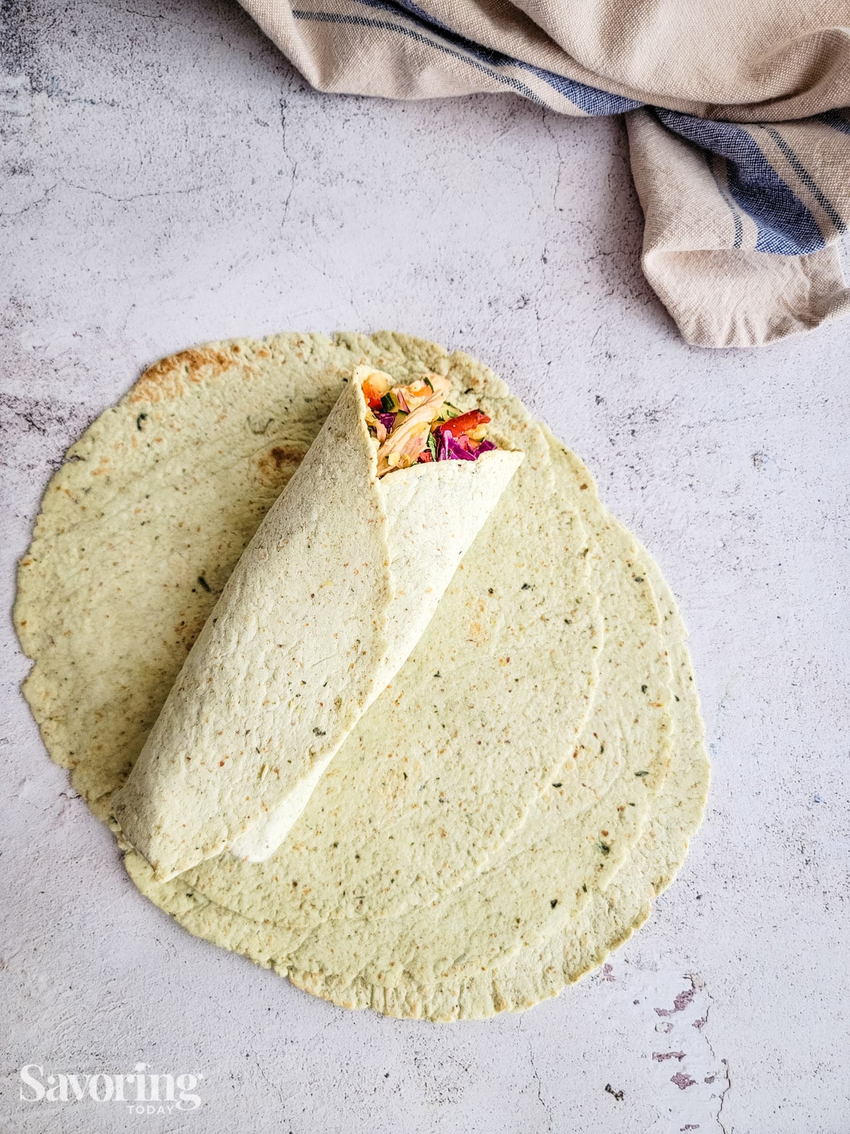 Chicken salad wrapped in a tortilla on a stack of tortillas