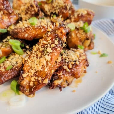 chicken wings sprinkled with chopped peanuts on a white plate