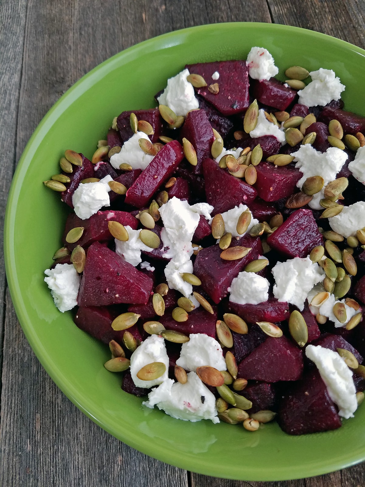 roasted beets with pepitas and goat cheese in a green bowl
