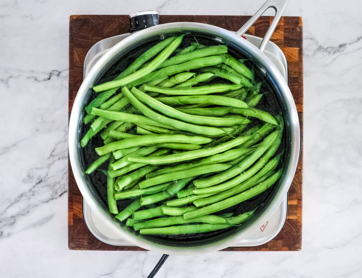 blanching green beans in a saucepan of water