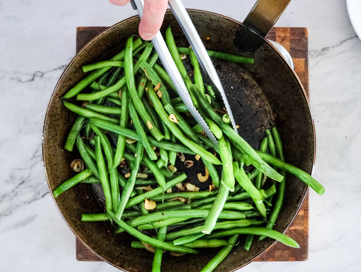 sauteeing green beans in a large skillet with shallots