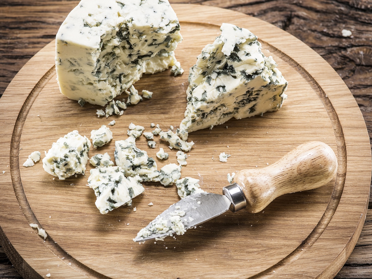 block of blue cheese on a cutting board with a cheese knife