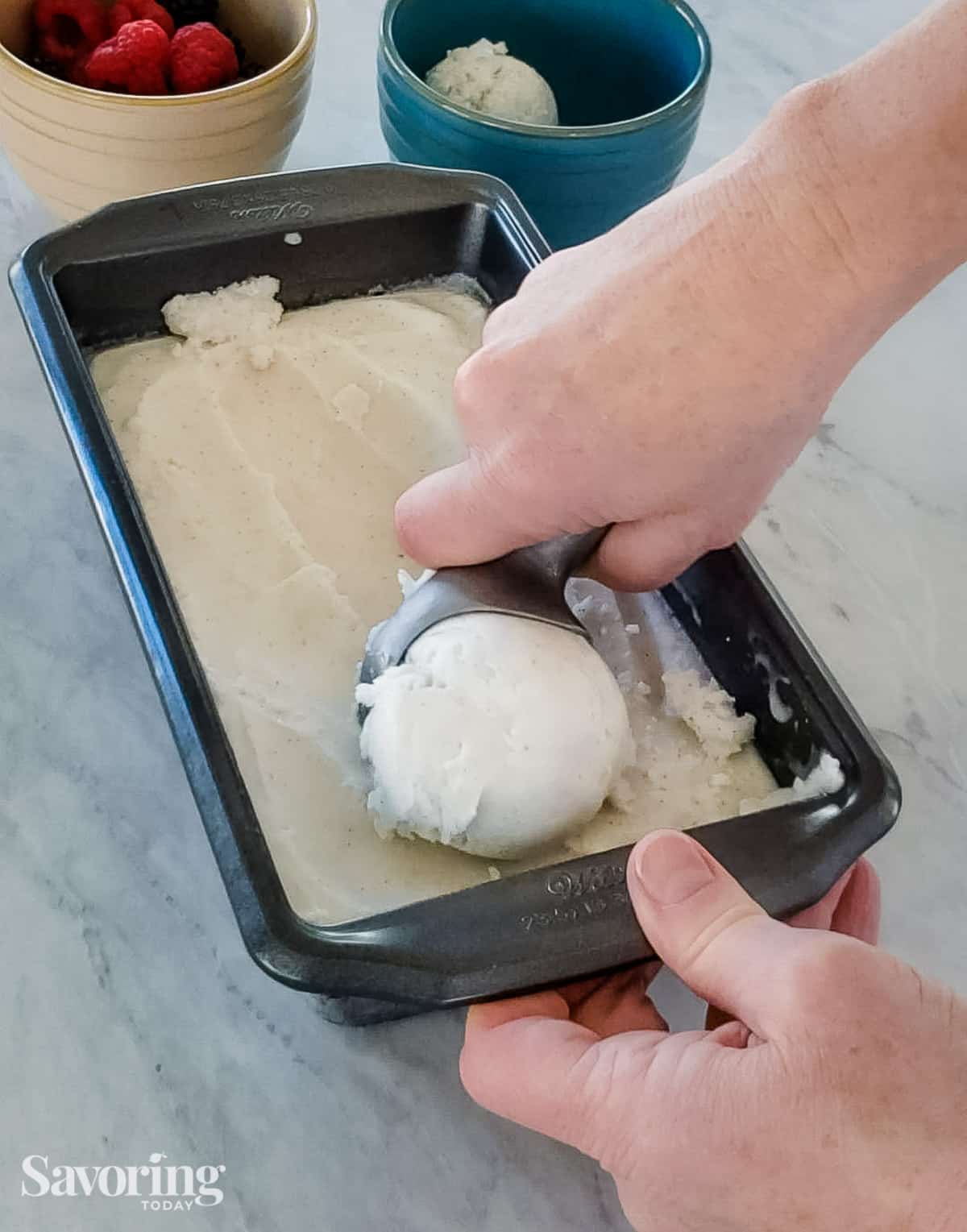 A hand scooping coconut sorbet out of a metal pan