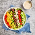 A salad with creamy dressing on a counter with a blue towel