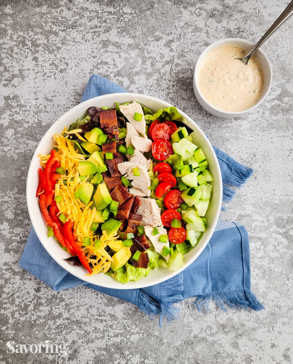 A salad with creamy dressing on a counter with a blue towel