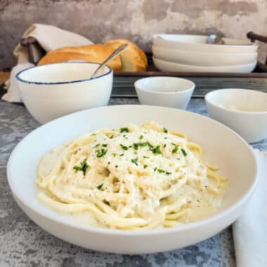 alfredo sauce over noodles in a white bowl