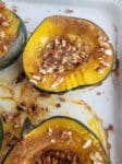 Roasted Acorn squash on a white baking dish topped with pecans