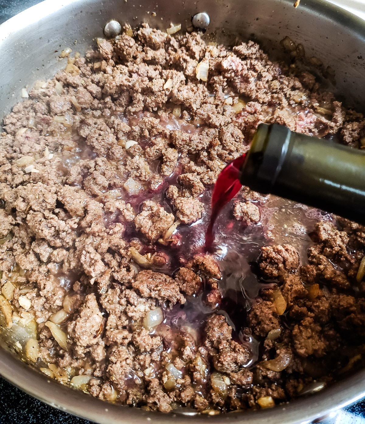 Pouring wine into skillet with browned beef