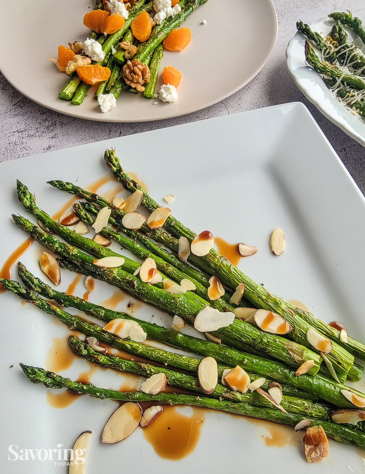 roasted asparagus with sliced almonds and aged balsamic vinegar on a square white plate