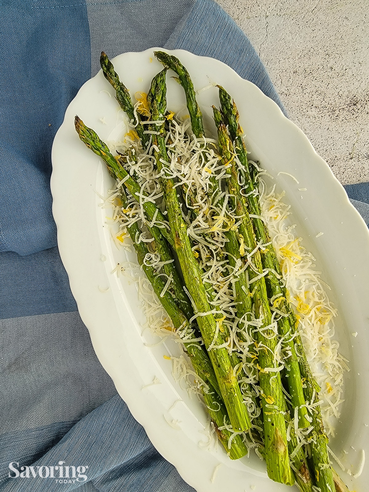 roasted asparagus on a white plate with parmesan and lemon zest on top