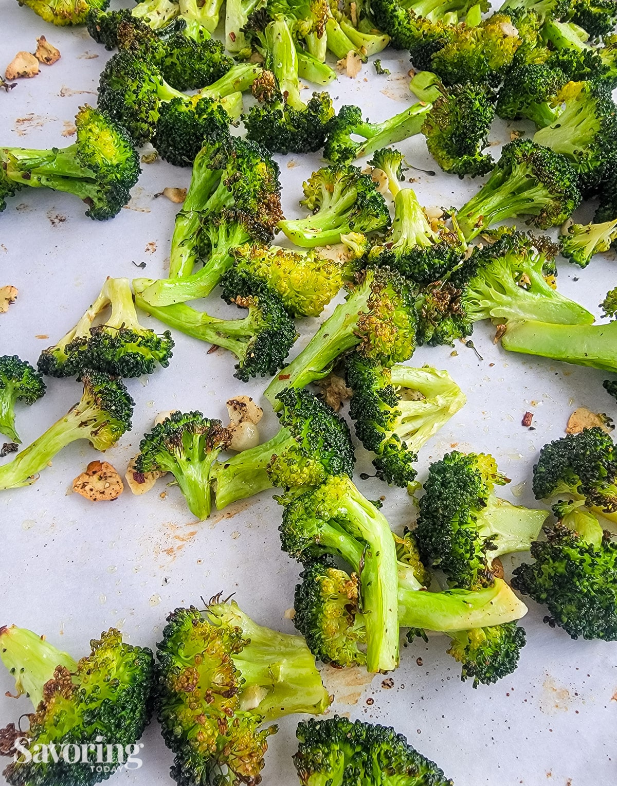 Broccoli on a sheet pan that has been roasted with sliced garlic.