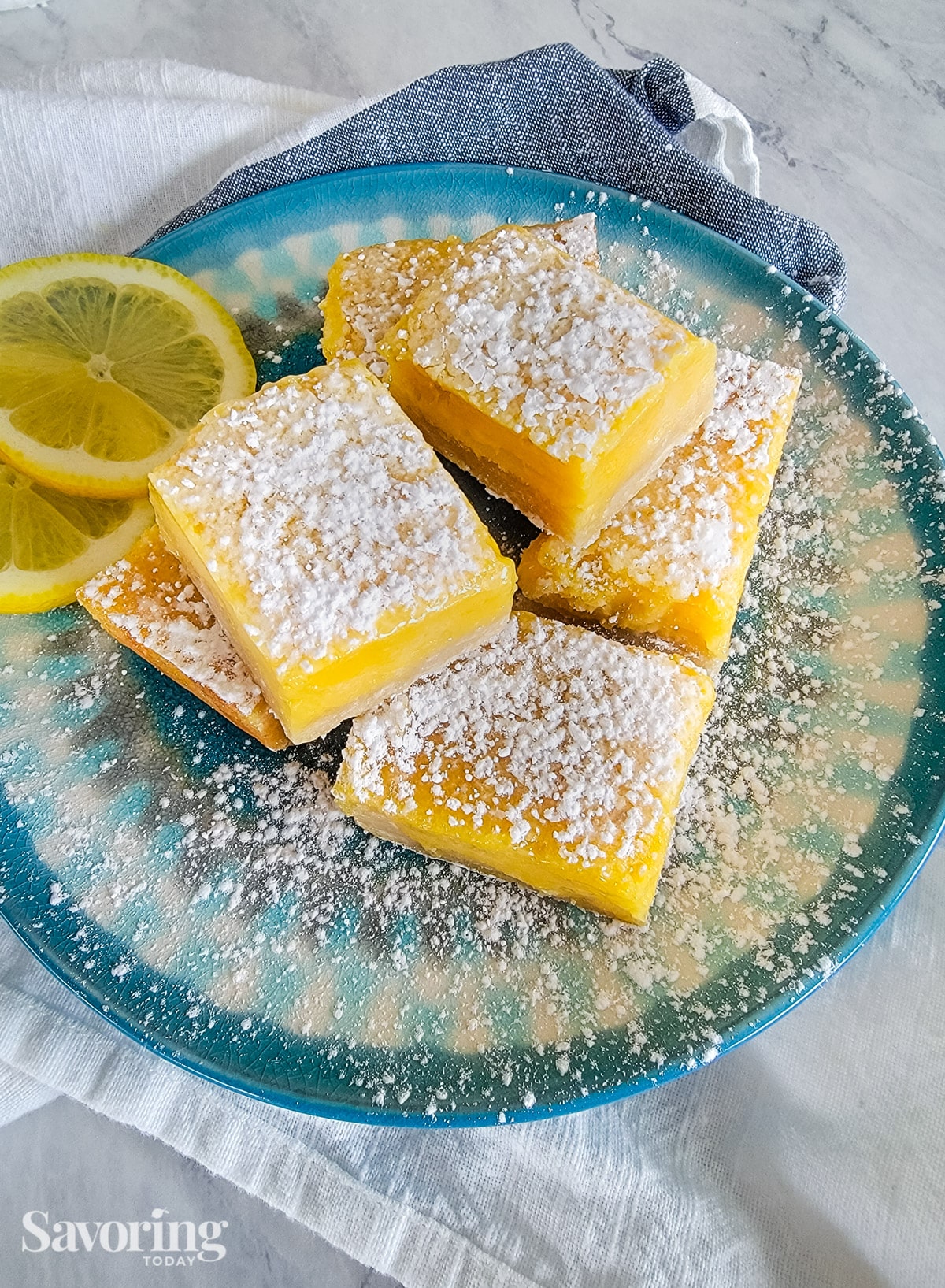 Lemon bars on a blue plate with powdered sugar on top