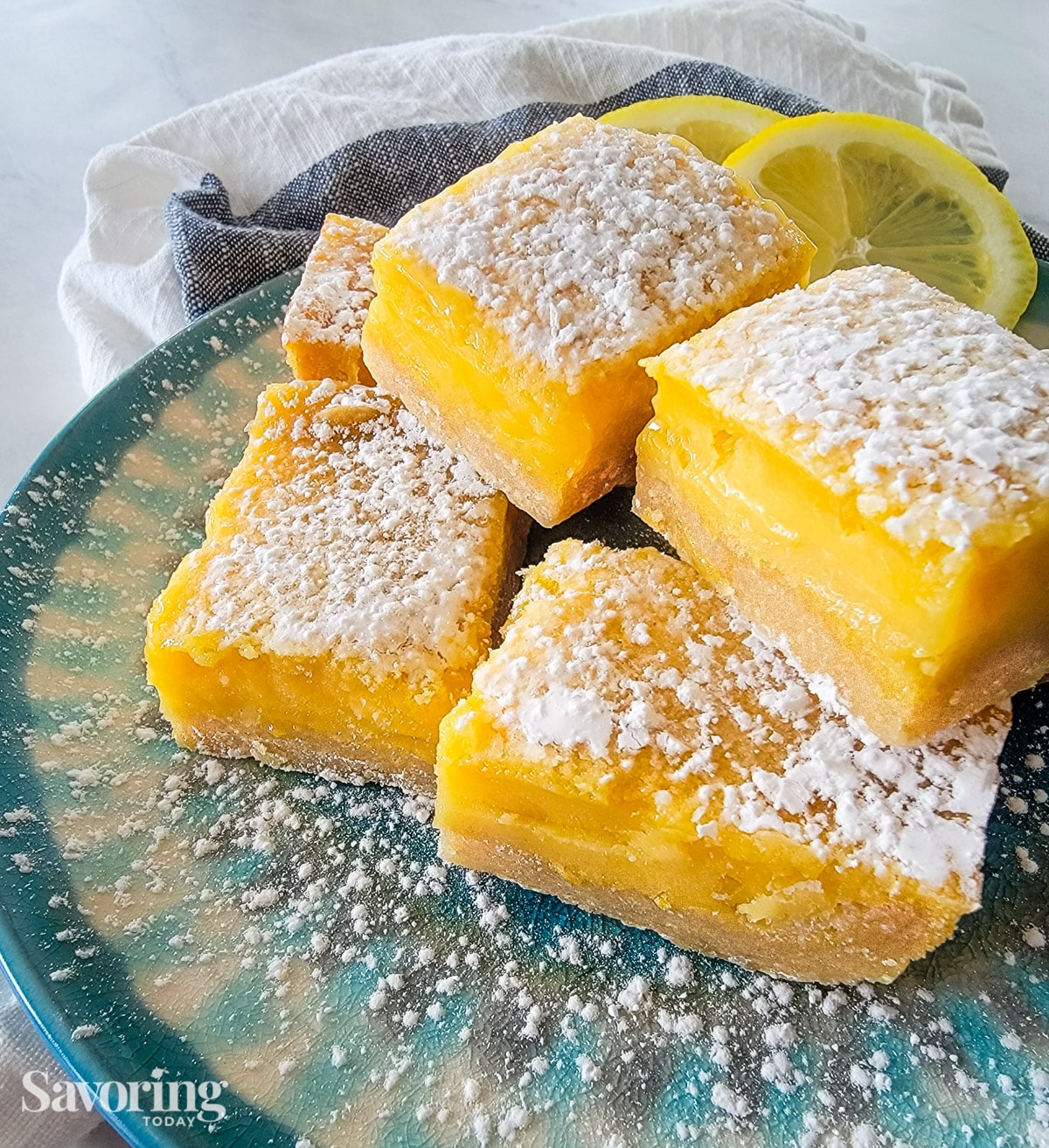 close up of lemon bars on a plate with a towel