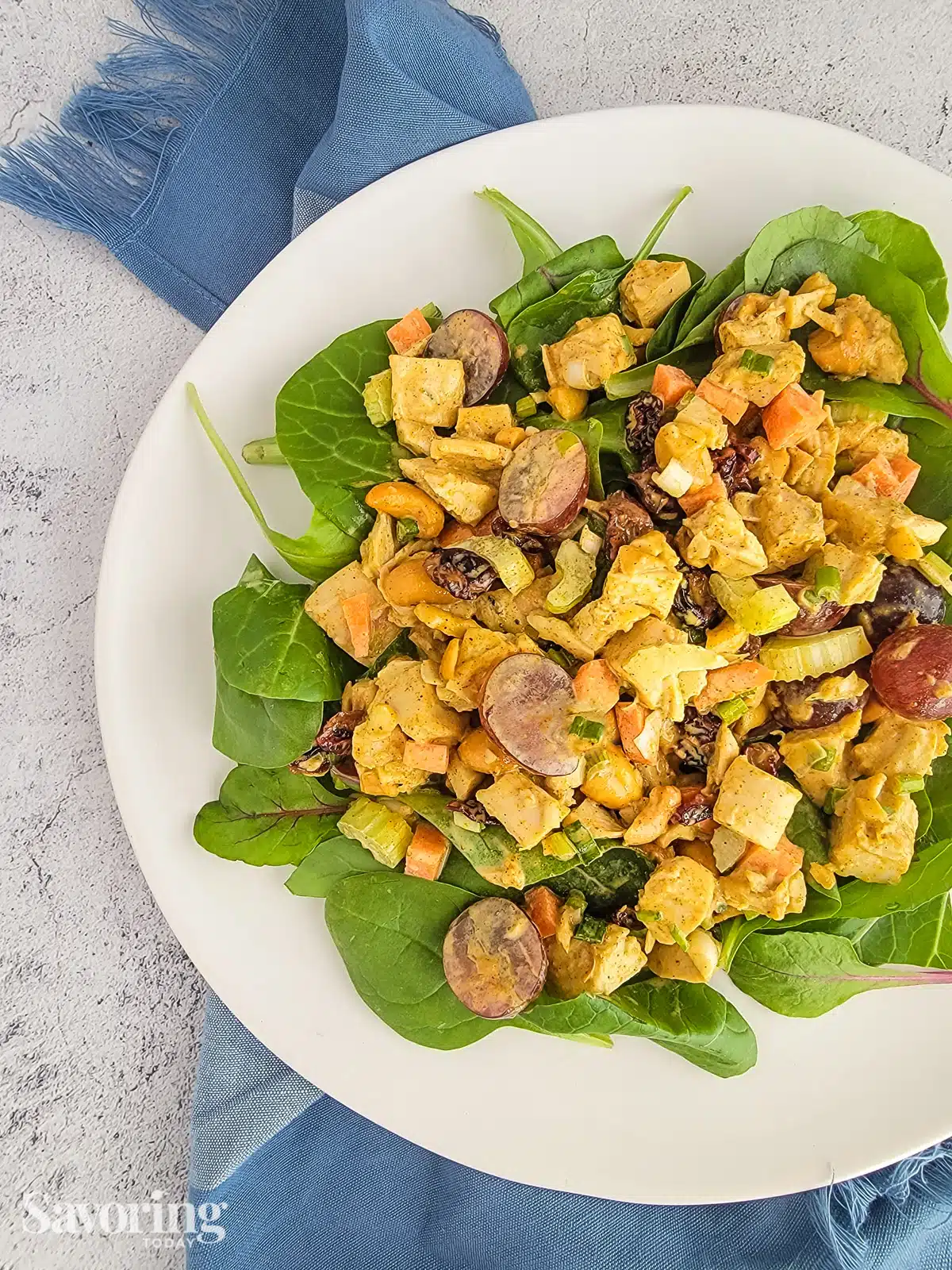 curry chicken salad over spring greens on a white plate