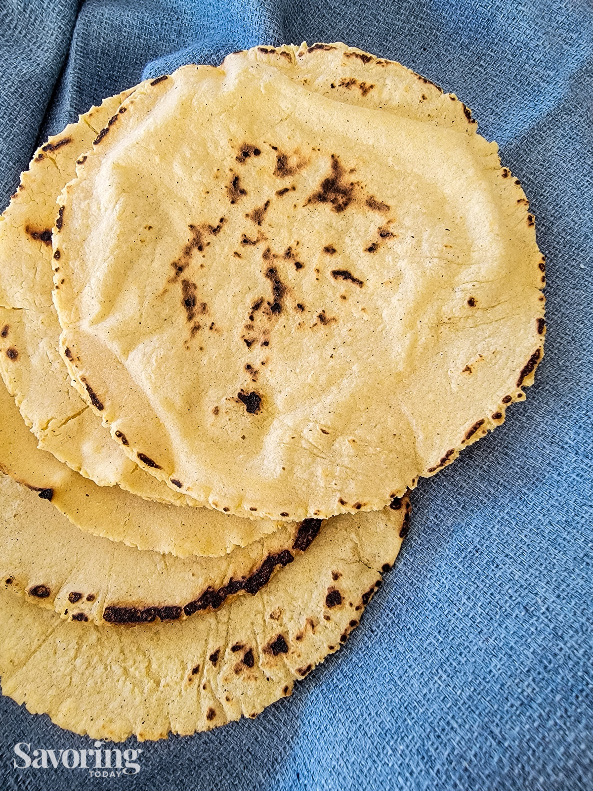 corn tortillas stacked and spread on a blue towel