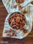 dehydrated pecans in a blue bowl over a towel on a table