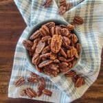 dehydrated pecans in a blue bowl over a towel on a table