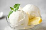 Close up of lemon ice cream in a clear bowl with lemon slice