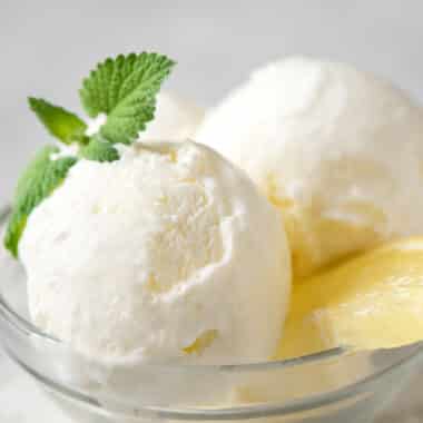 Close up of lemon ice cream in a clear bowl with lemon slice