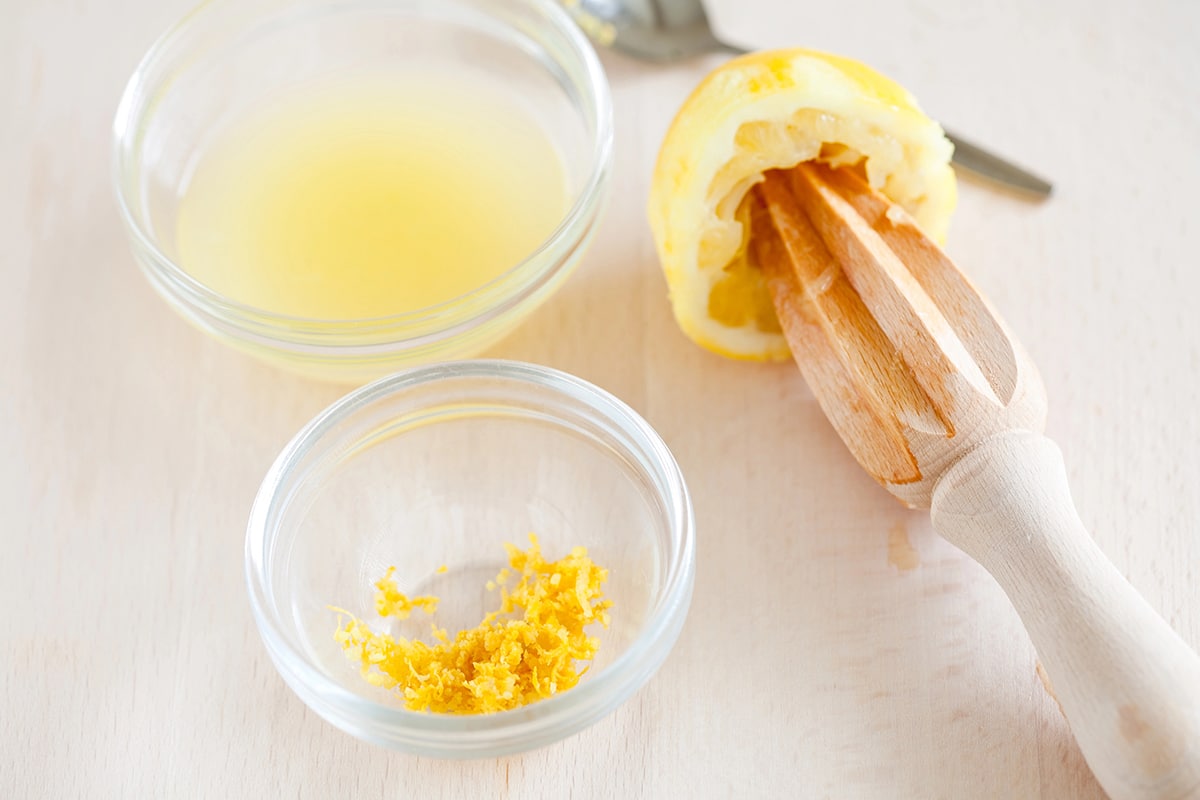 Lemon juice and zest in bowls beside a hand juicer