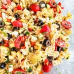 pasta salad with vegetables and cheese in a clear bowl