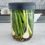 pickled green beans with fresh garlic in a jar with a grey lid
