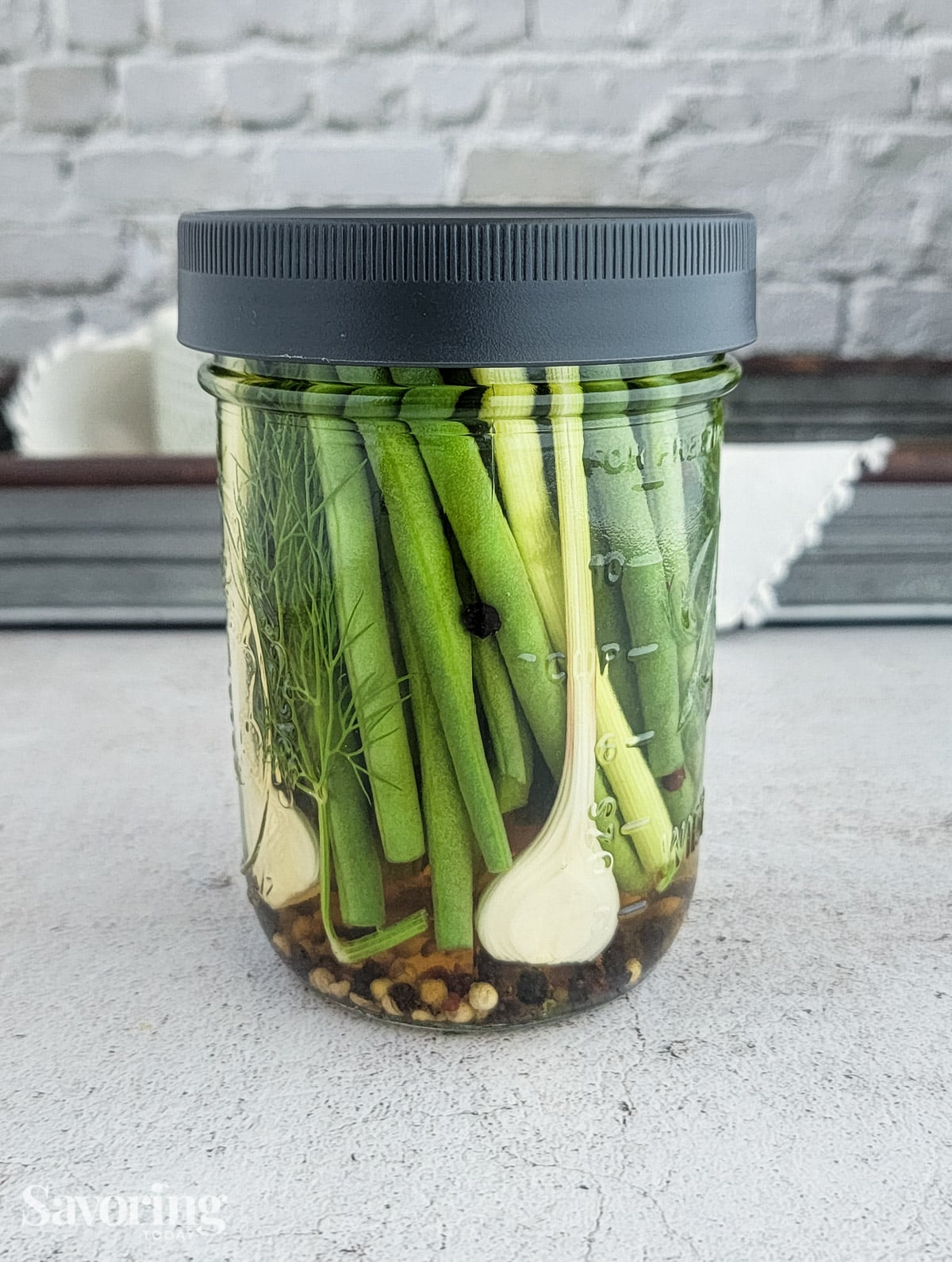 pickled green beans with fresh garlic in a jar with a grey lid