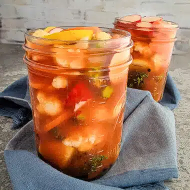 mixed vegetables pickled in pint jars on a blue towel