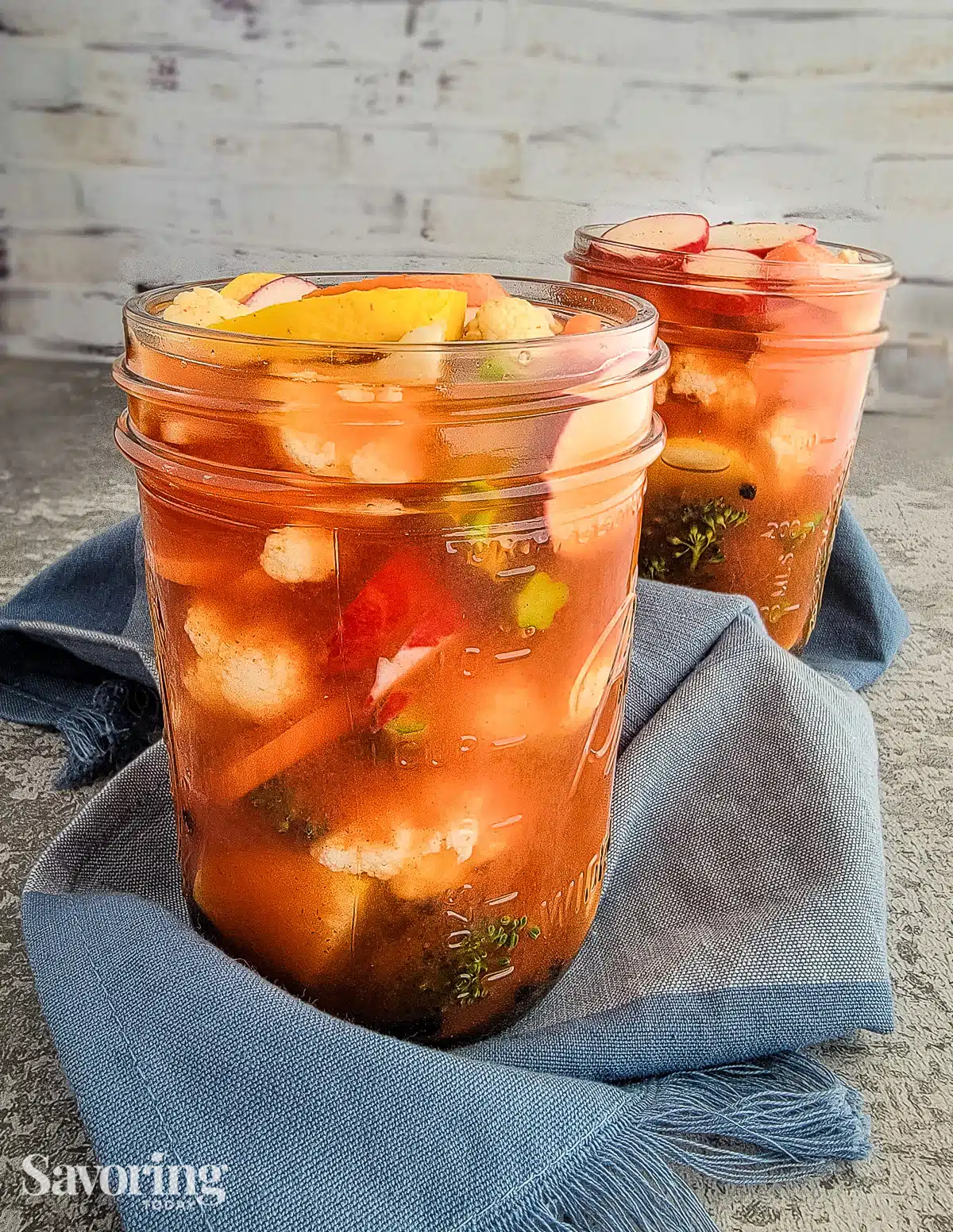 mixed vegetables pickled in pint jars on a blue towel