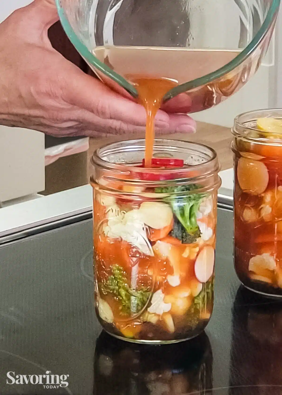 pouring pickle brine into a pint jar of chopped vegetables