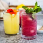 ginger lemon switchel garnished with flowers and mint on a grey counter