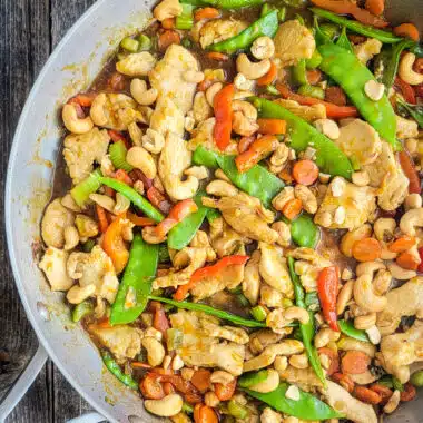 Orange Cashew Chicken Stir-Fry in a skillet on a wood table