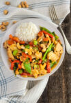 orange cashew chicken with white rice in a white bowl