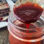 raspberry sauce on a spoon over a jar