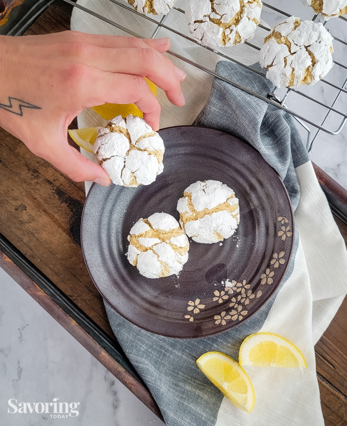 A hand picking up a lemon cookie from a plate of cookies