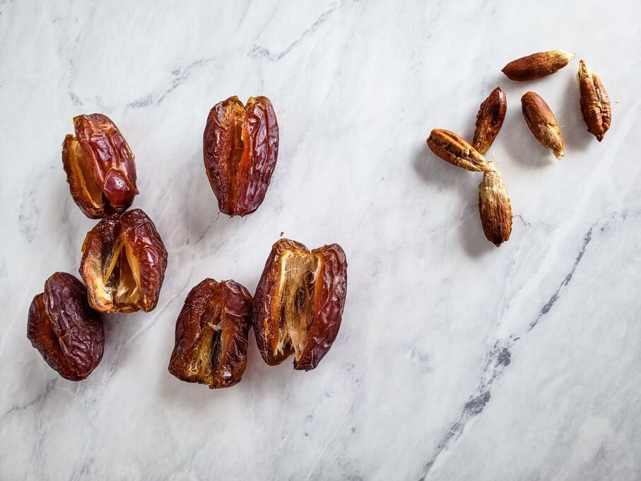 dates split open with pits removed laying beside them