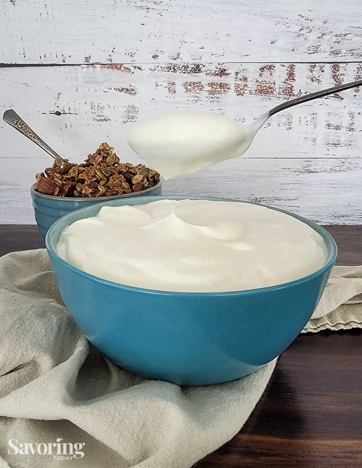 A bowl of yogurt with a spoonful held above it.