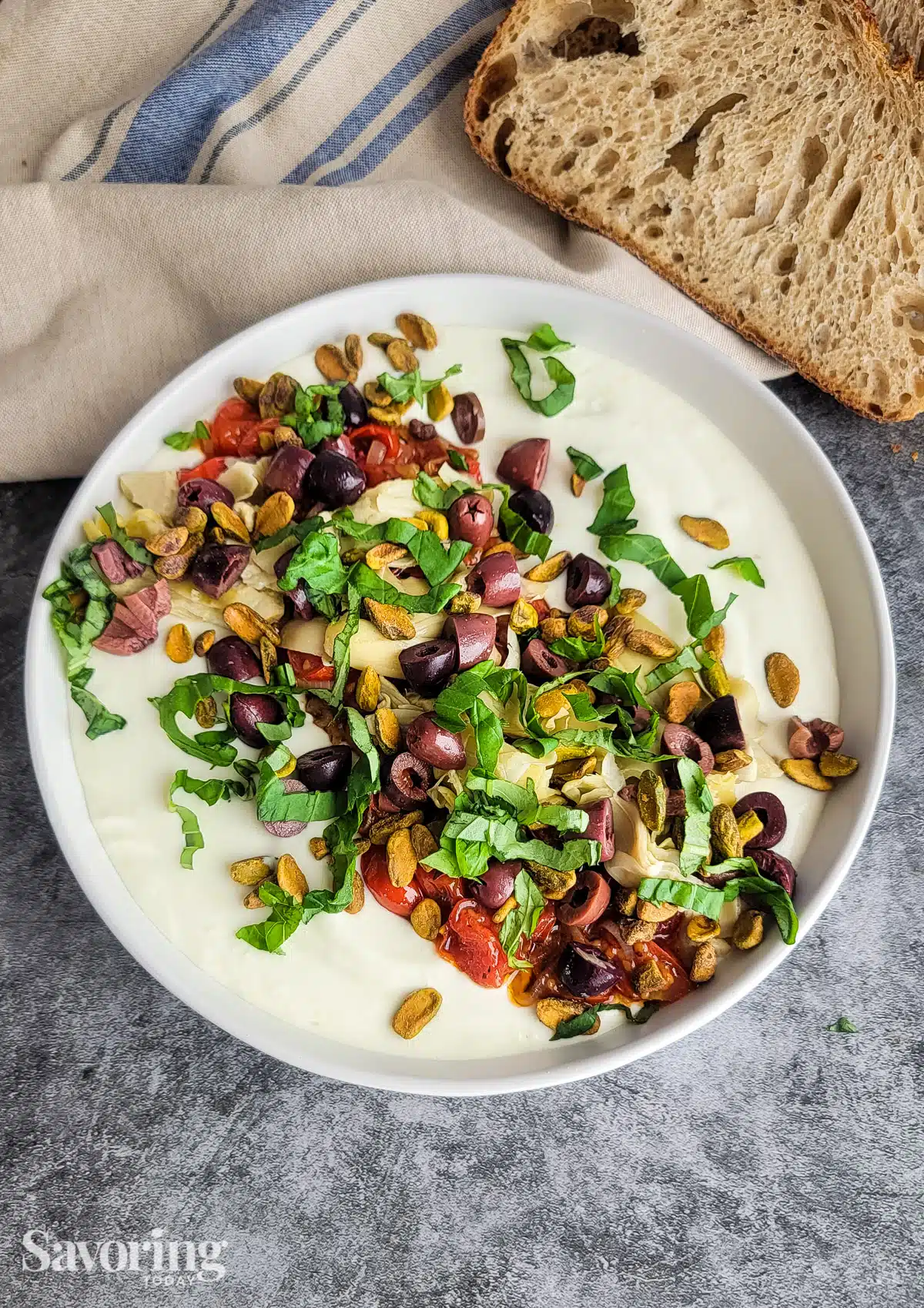 Savory ricotta feta dip in a white bowl with bread on a counter ready to serve