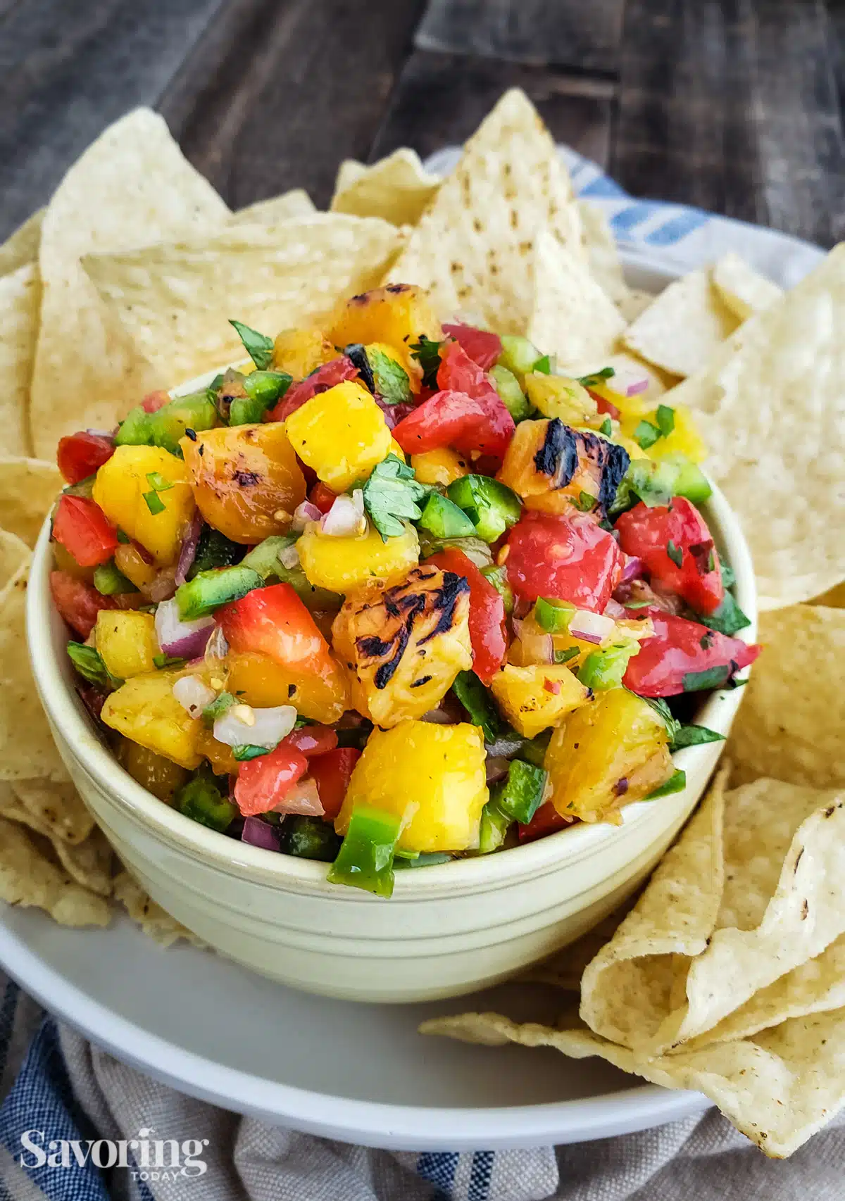 Mango pineapple salsa in a white bowl surrounded by chips