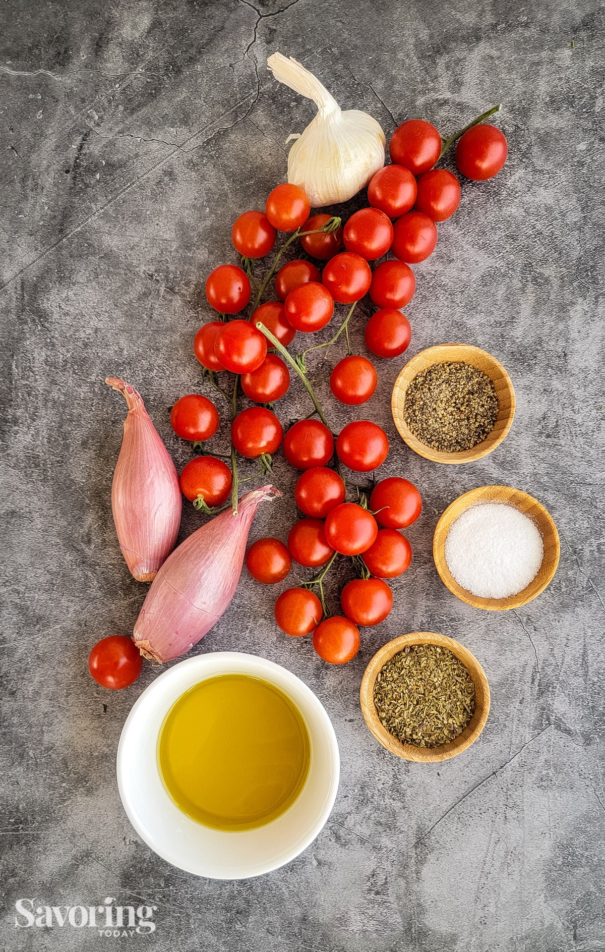 grape tomatoes, shallot, grlic, oil, and herbs on a counter 