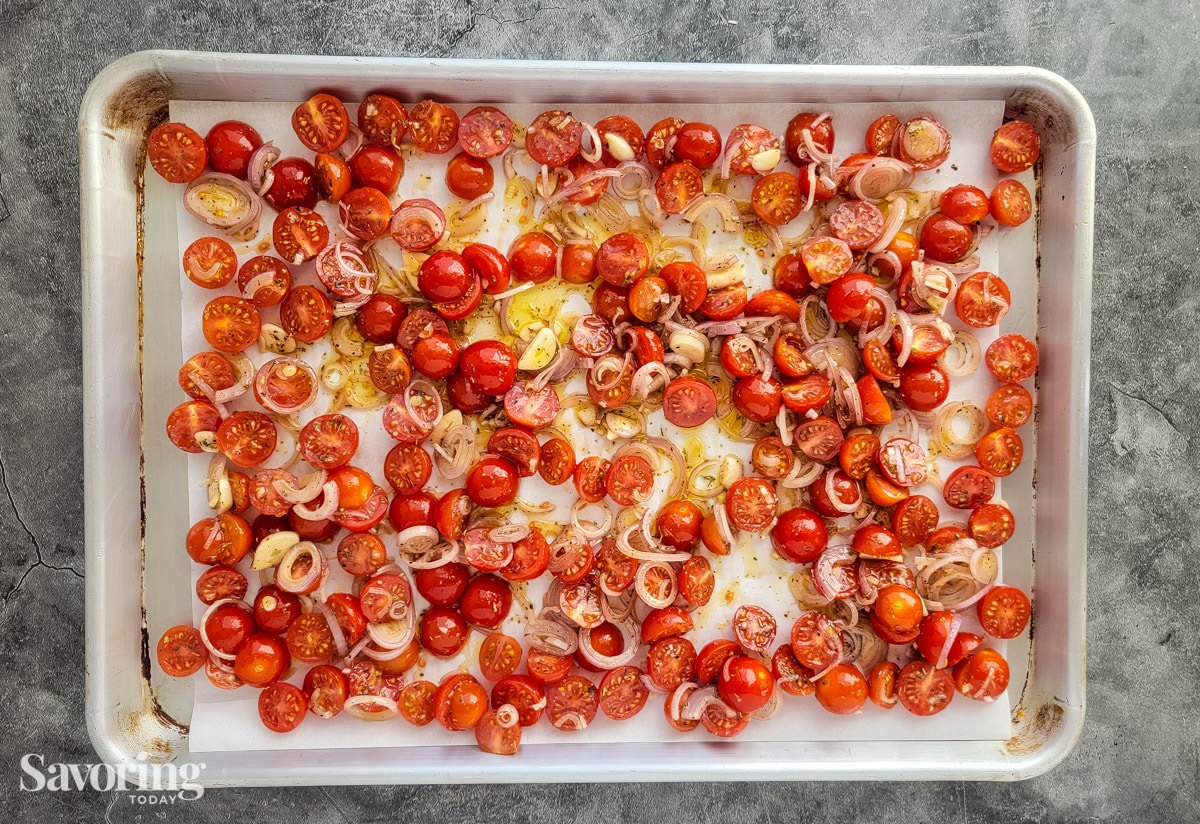 grape tomatoes, shallots, and garlic on a pan with olive oil