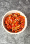 roasted tomato, shallots, and garlic in a white bowl on a grey countertop